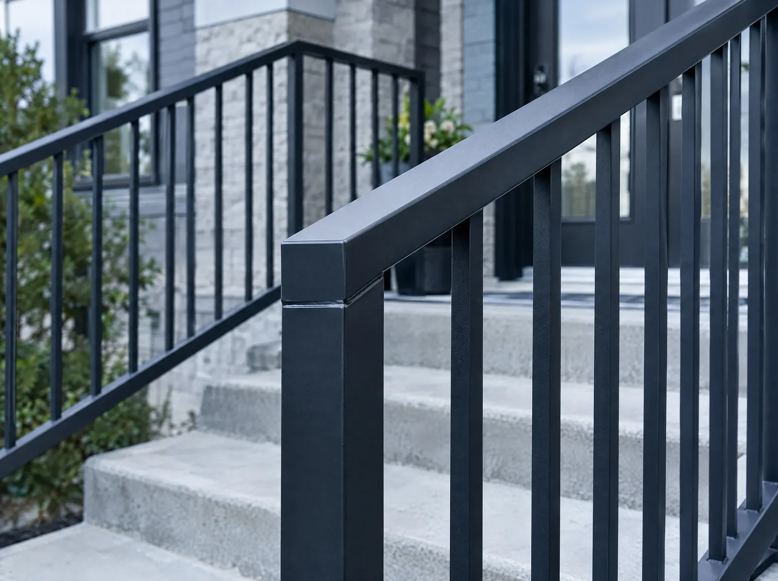 Black powder-coated steel picket railing on the concrete entrance steps of a condominium